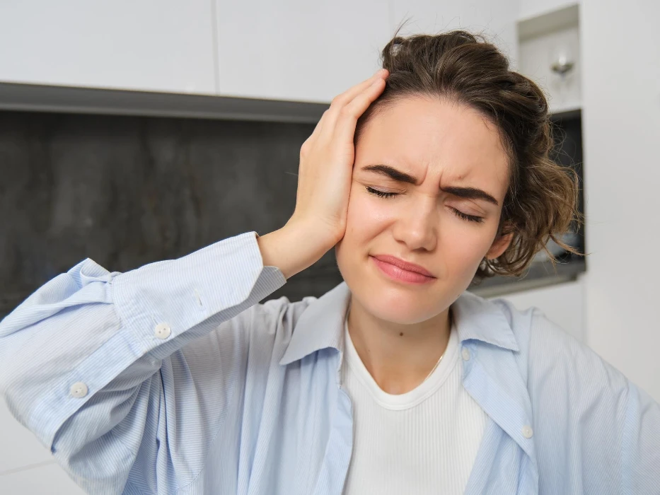 Close up portrait of brunette woman touches her head feels dizzy has migraine or headache grimaces f